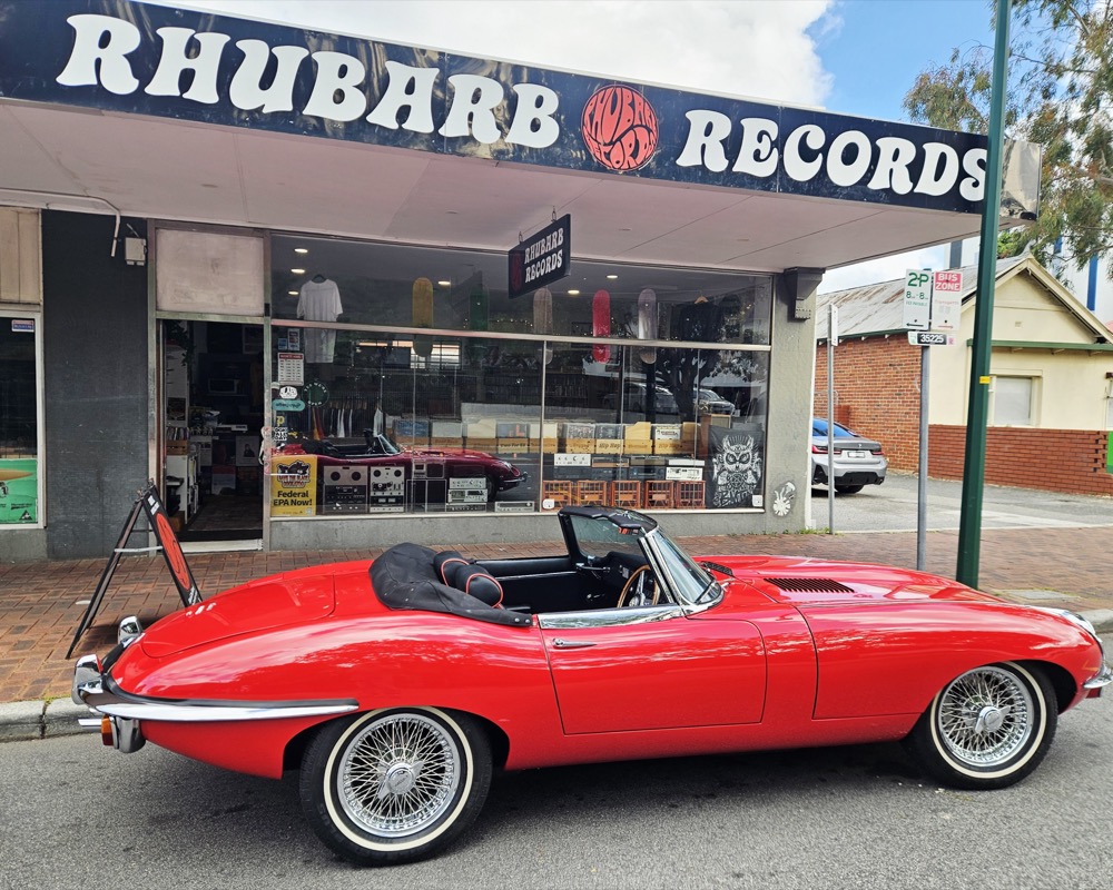 Side view of the shopfront and its big Rhubarb Records sign, with the red Jaguar out the front